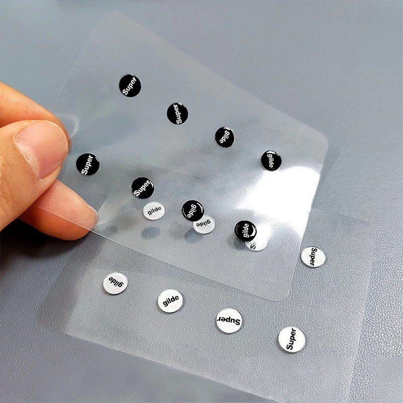 Hand holding 8-pack universal glass mouse skates with adhesive backing